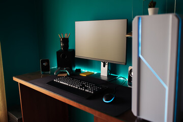 Modern stylish black gaming computer with keyboard and speakers placed on table near joystick lamp and stationery