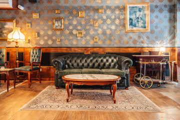 Comfortable vintage interior of spacious hall of restaurant with stylish armchairs and sofa under crystal chandeliers