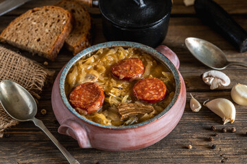 Christmas cabbage soup in ceramic bowl on natural wooden background.
