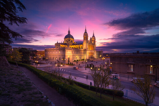 Majestic view of Almudena Cathedral with illuminated exterior on background of pink sundown sky in Madrid
