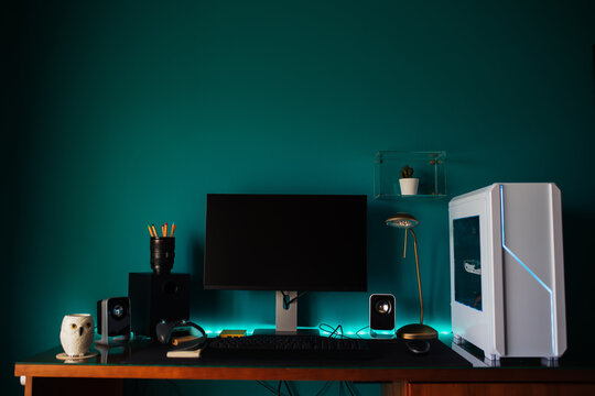Modern stylish black gaming computer with keyboard and speakers placed on table near joystick lamp and stationery