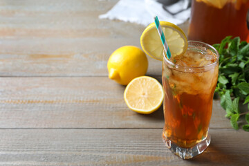 Delicious iced tea in glass on wooden table, space for text