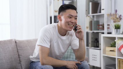 joyful korean young male in parlor is answering a call from and catching up with an acquaintance happily.
