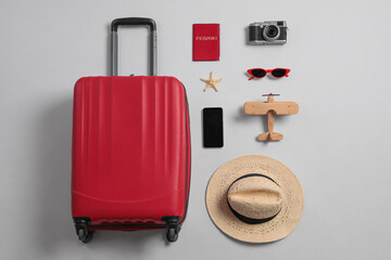 Flat lay composition with suitcase and travel accessories on grey background. Summer vacation