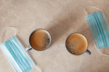 a couple of cups of coffee on the table, next to the medical masks. The concept of lifestyle, a new life in the pandemic. Valentine's Day during the coronovirus