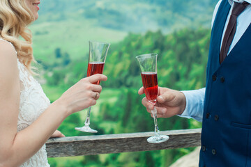Glasses with red champagne drink in bride and groom hands. Happy newlyweds drinking. Loving couple created new family.