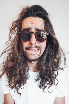 Young hipster long haired bearded male in sunglasses with funny amazed face expression looking at camera while taking selfie