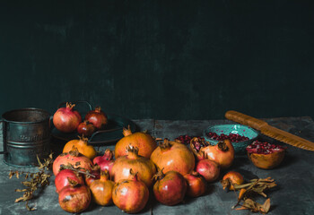 Pile of colorful fresh pomegranates arranged on table with dried plants