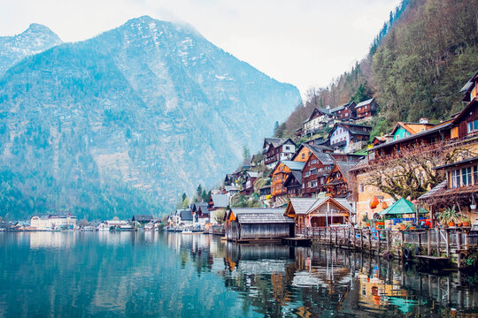 Picturesque landscape of traditional residential houses and famous Lutheran Parish Church of Hallstatt located on lake shore surrounded by mountains in Austria