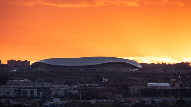 Spectacular view of Wanda Metropolitano Stadium with curved roof on background of orange sundown sky in Madrid