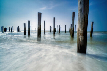 Long exposure seascape. Taken at the North Sea in Petten with the pole village in the sea, Blue sky, sun and shodows. Focus on foreground