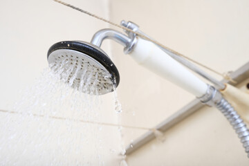 Water flowing from an old shower head with ceramic handle with limescale needed to be replaced or decalcified