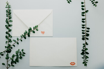 Minimal composition with a white envelope, heart and green leaves