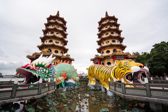 Low angle exterior of traditional oriental pagodas with colorful ornamental Tiger and Dragon sculptures built on lake and connected with shore by stone bridges in Kaohsiung city in Taiwan