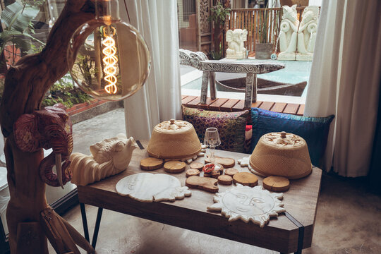 Table with various wooden coasters and bamboo food covers arranged in room with traditional decorations in hotel of Taiwan