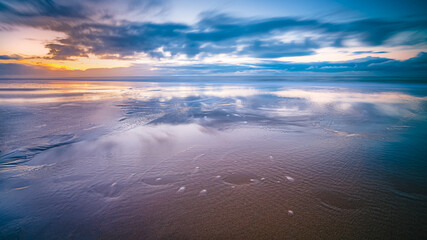 The sunset with the reflection of clouds in low tide water in Waddenzee, Texel, The Netherlands