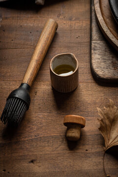 From Above Of Silicone Pastry Brush And Jar Of Olive Oil Arranged On Wooden Table In Rustic Kitchen