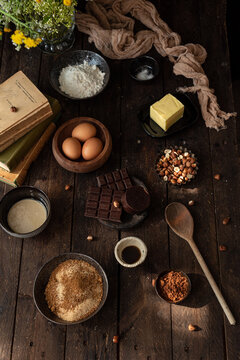 Top view set of various ingredients for sweet chocolate pastry with hazelnuts arranged on wooden table