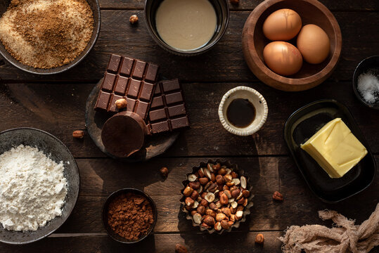 Top view set of various ingredients for sweet chocolate pastry with hazelnuts arranged on wooden table