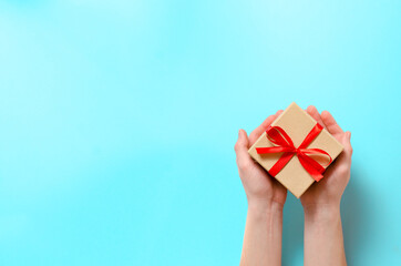 Festive composition. Consists of hands holding a gift box on a blue background. Top view with place for your text.