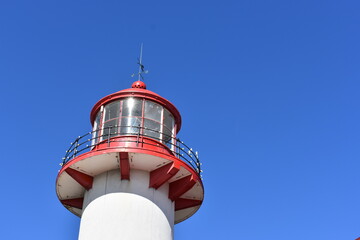 top of red and white lighthouse in the blue sky