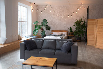 Modern studio apartment design with bedroom and living space. Hotel room with panoramic window, king sized bed, couch and coffee table. City flat concept.