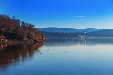 Brno Dam Czech Republic Europe. Water surface and dam. In the background is the housing estate Bystrc and Kohoutovice. The sky is blue with white clouds