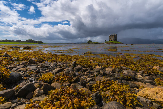 Distant view of magnificent ancient Castle Stalker located near calm lake in Scotland