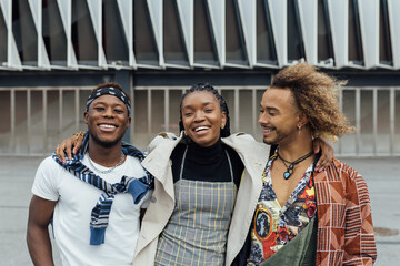 Group of cheerful young African American hipster friends in trendy outfits looking at camera and smiling happily on urban street