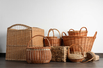 Many different wicker baskets made of natural material on floor near light wall