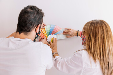 Back view of male worker and woman with paper palette picking color for walls during renovation process in apartment