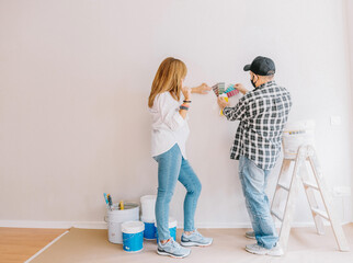 Back view of male worker and woman with paper palette picking color for walls during renovation process in apartment