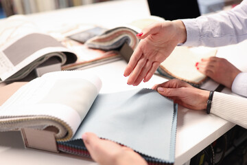 Women holding catalog and choosing fabrics closeup