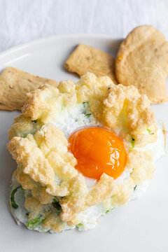 High angle of appetizing homemade baked cloud eggs with green vegetables served with crispy crackers for healthy breakfast