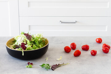 Salad green leaves in bowl placed in table with fresh tomatoes