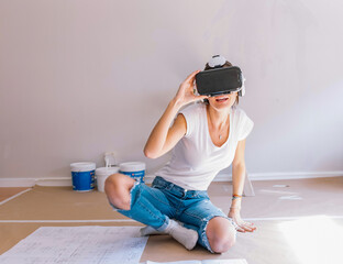 Young woman in VR headset gesticulating while visualizing apartment plan in cyberspace during renovation at home