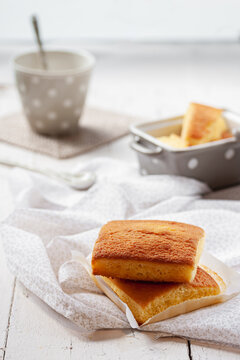 Typical Spanish sobao pasiego cakes served for breakfast with cup of hot drink on wooden table with tablecloth