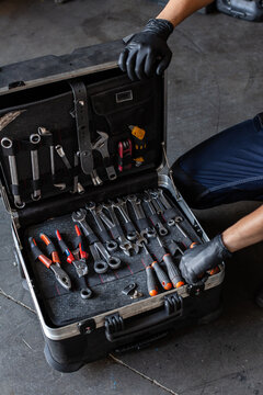 From above unrecognizable male technician picking screwdriver bits from tool box while working in garage