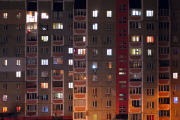 Fototapeta na wymiar Lighted windows in nocturnal high-rise building. Modern house of flat at night