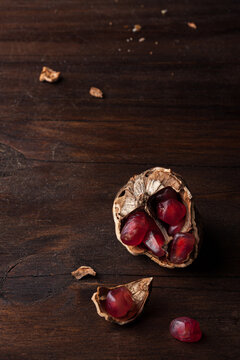 Top view still life composition with ripe red pomegranate seeds arranged in walnut shells on dark wooden background