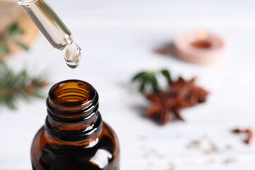 Dropping anise essential oil from pipette into bottle on table, closeup. Space for text