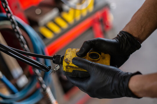 Side view of crop hands of anonymous mechanic in protective gloves using special tool for control and diagnostic of machine engine while working in workshop