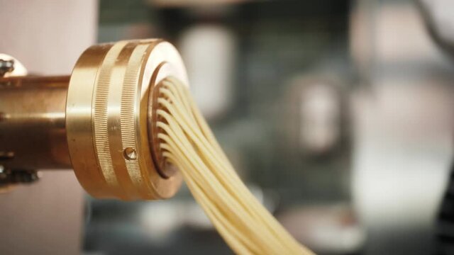 Man making fresh pasta on traditional italian kitchen, machine for spaghetti, chef preparing fresca dough, italy factory
