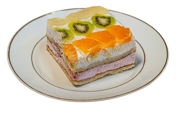 home-cooked biscuit cake with a layers of home-made cottage cheese decorated with tropical fruits on white plate isolated on white