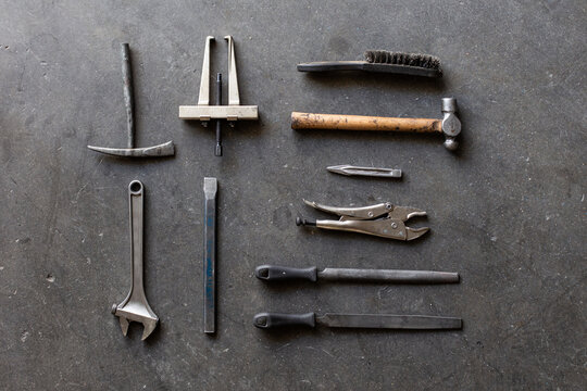 Top view of assorted shabby repair tools placed on grungy gray floor of workshop
