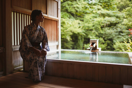 Young caucasian woman in a kimono getting ready to enjoy.a relaxing and traditional thermal waters bath at a Japanese onsen, side view