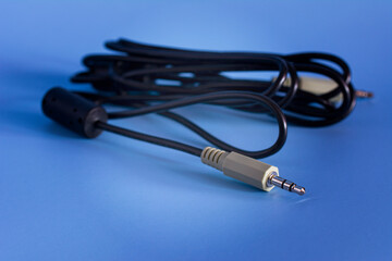 Black aux audio cable on the blue background. Standard 3.5mm Male to Male speaker cable. Use To connect an external audio source.