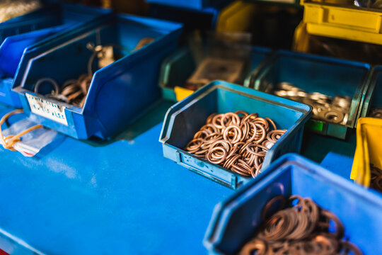 High angle of blue containers with many copper rings placed on workbench in garage