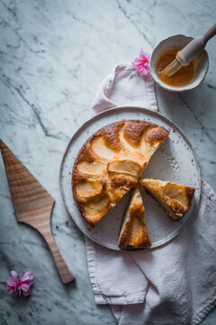 Top view composition with delectable homemade apple cakes on plates placed on table with bowl with sweet syrup and cooking brush
