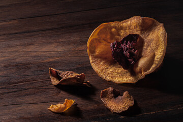Still life chiaroscuro composition with dehydrated sliced sweet potato and beet arranged in shape of flower on wooden surface